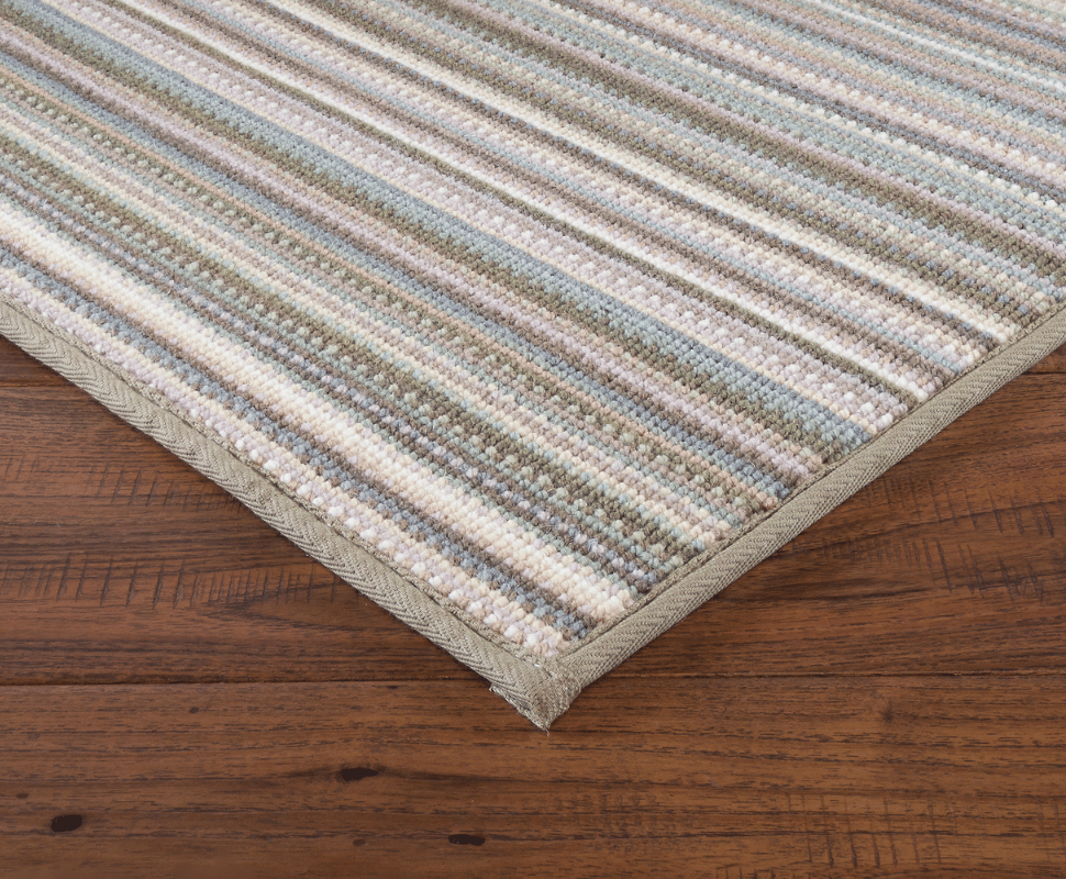 Taupe serged border wrapping a cool neutral wool carpet with soft slate blue, sage, and ivory stripes.