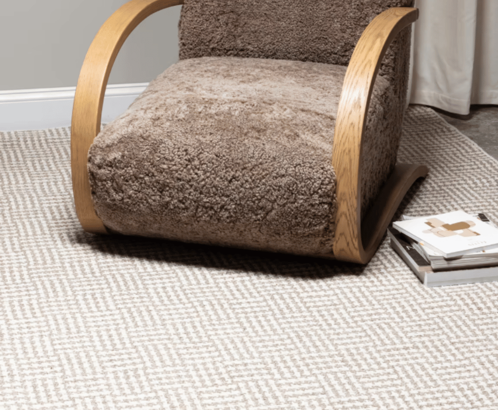 Plush brown lounge chair and magazines styled over a Sandstone basketweave flatweave wool carpet.