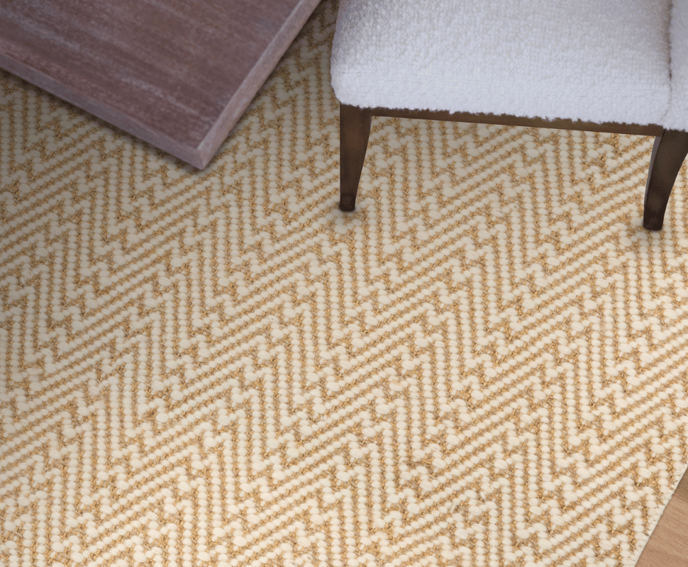 Top-down view of a wooden table edge and white boucle chair positioned on Kravet Durban Natural carpet.