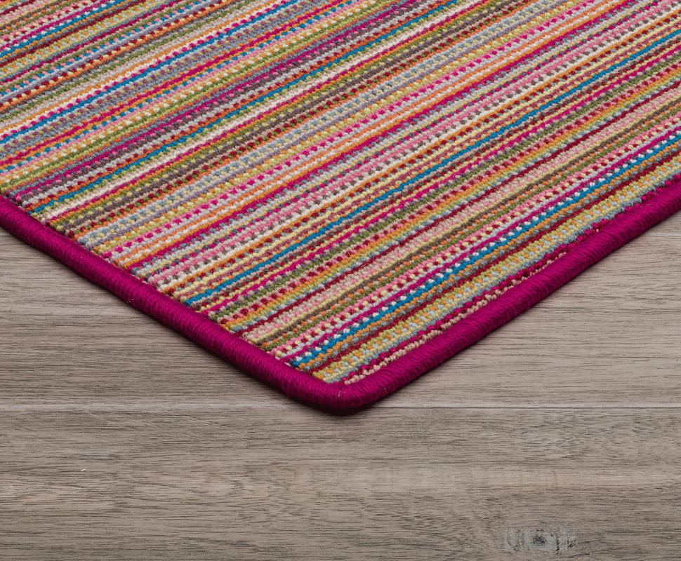 Magenta border finishing a vibrant wool loop carpet with electric pink, turquoise, and gold stripes.